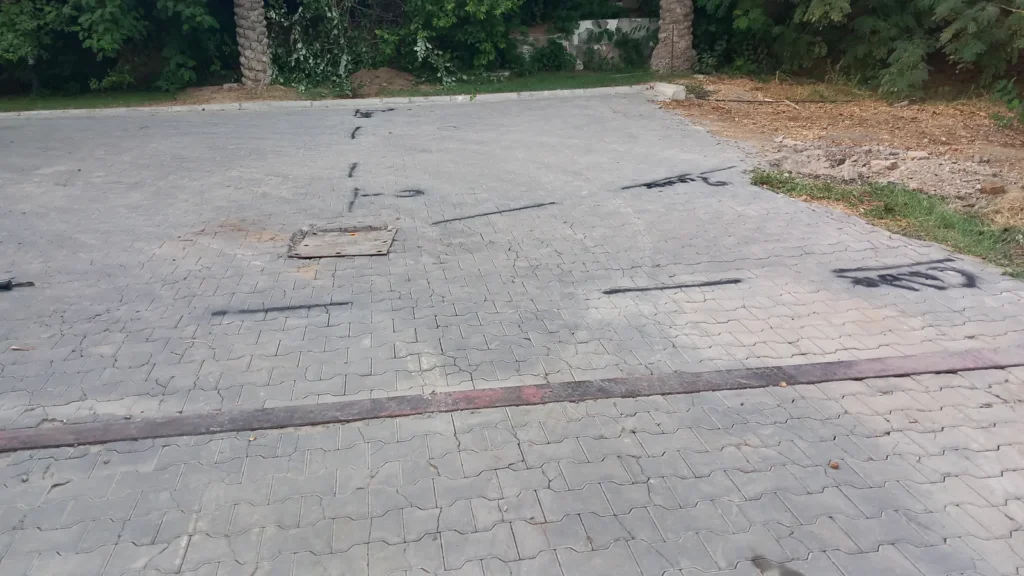 Traced utility runs and a chamber cover marked in paint across block paving after the survey
