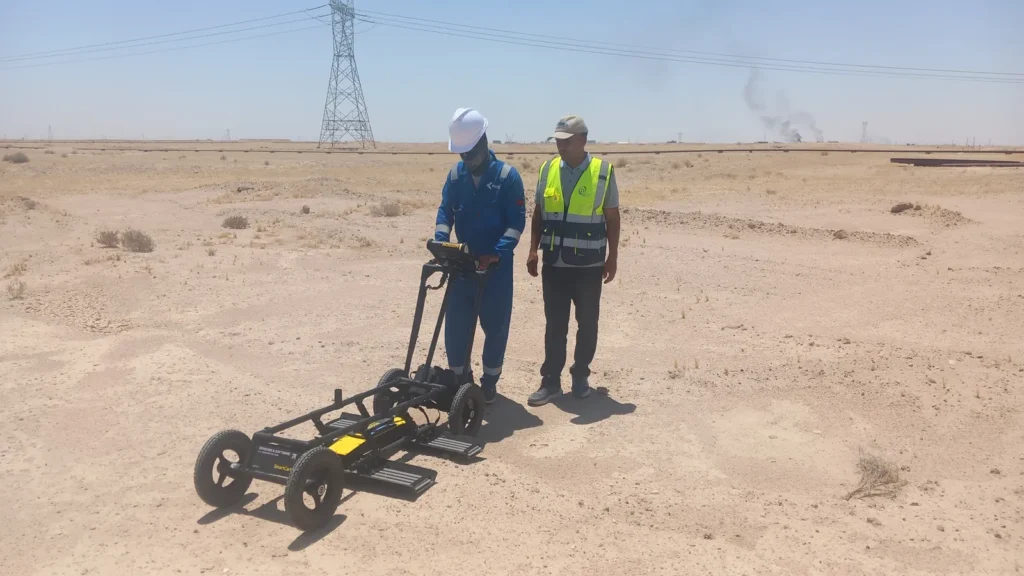 Noggin 100 MHz GPR cart being operated in open desert near Basrah, with a transmission tower and gas flare beyond